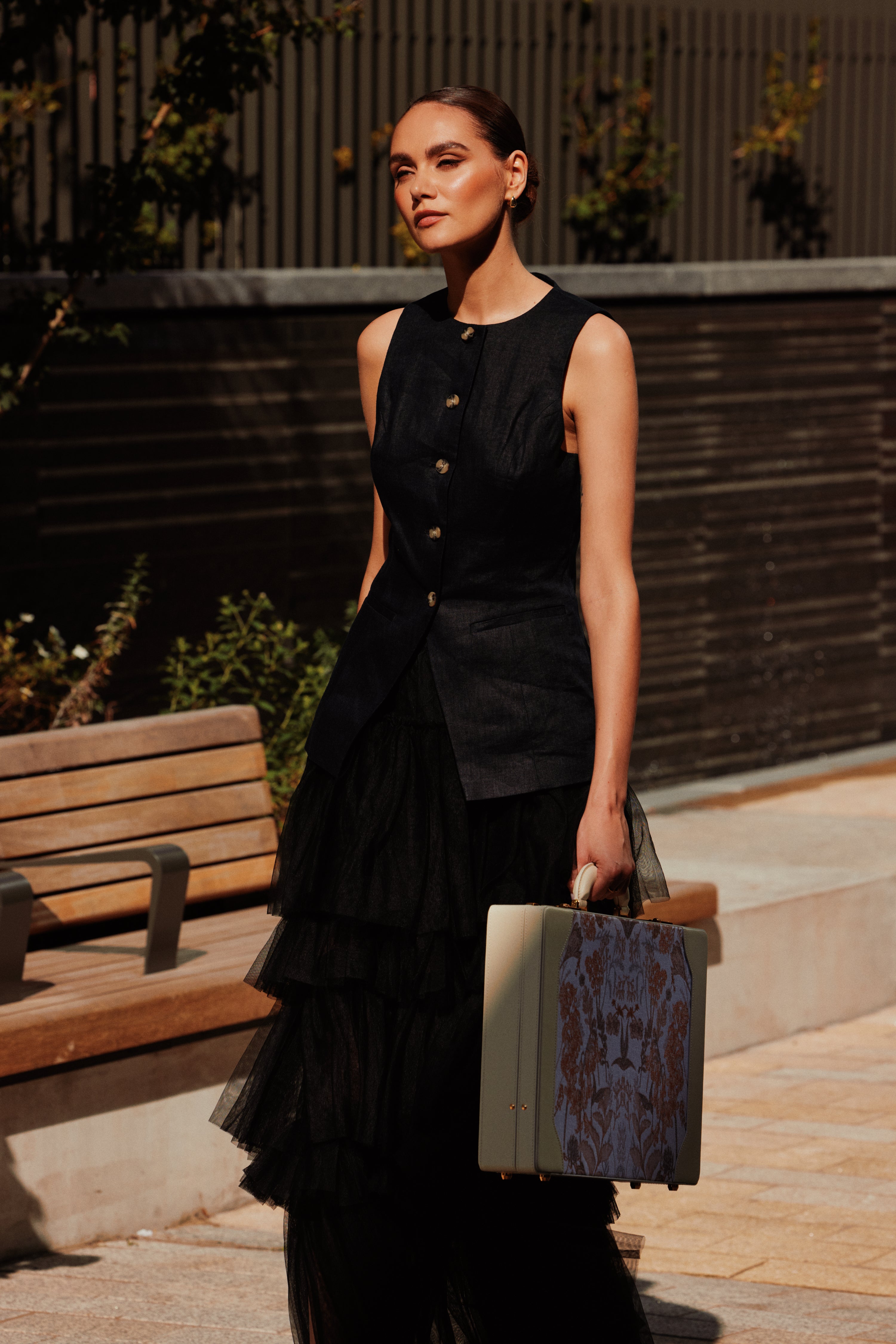 Woman in black holding the For All Daughters latte briefcase showing Irish jacquard fabric and Italian leather craftsmanship